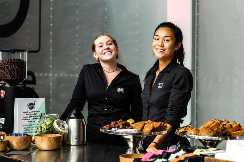 Circulaire beurs - twee dames van de catering achter de toonbank met verschillende versnaperingen