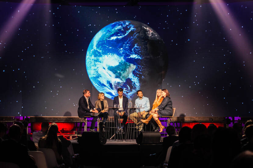 Circulaire beurs - groepsgesprek op podium met op de achtergrond een foto van de aarde