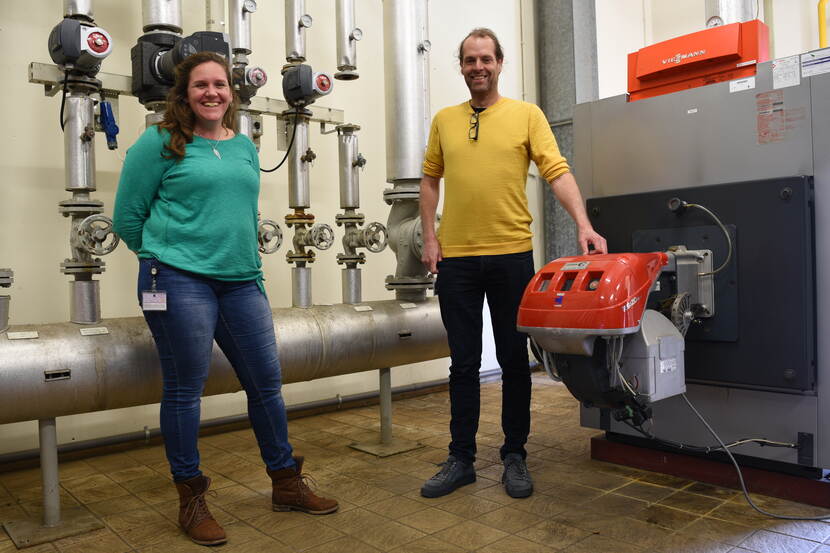 Suzan Otten en Stefan van Kaam staan bij de warmteinstallatie van Defensie