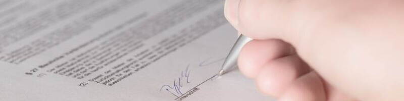 Een hand zet een handtekening onder een contract