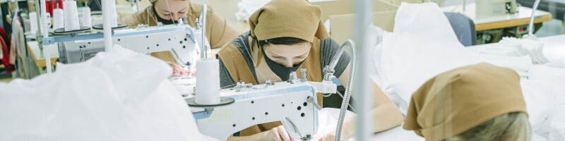 Vrouwen zitten achter een naaimachine te werken.