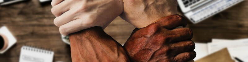 Handen van verschillende huidskleur houden elkaar vast.